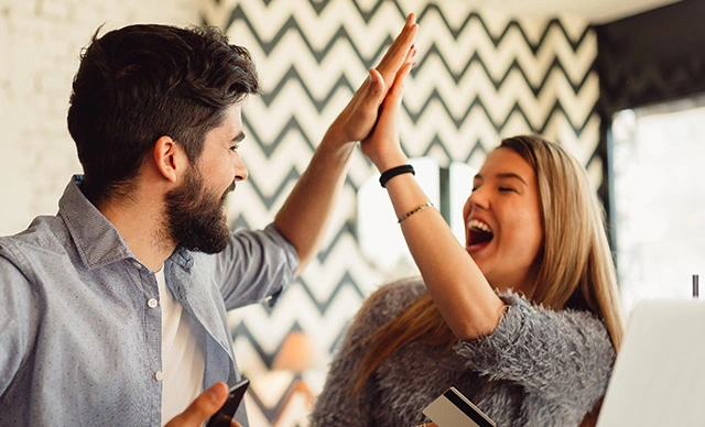 A couple in a cafe giving each other a high-five