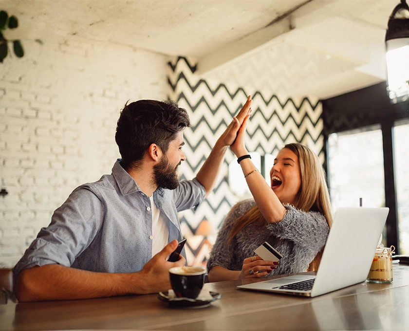 A couple in a cafe giving each other a high-five