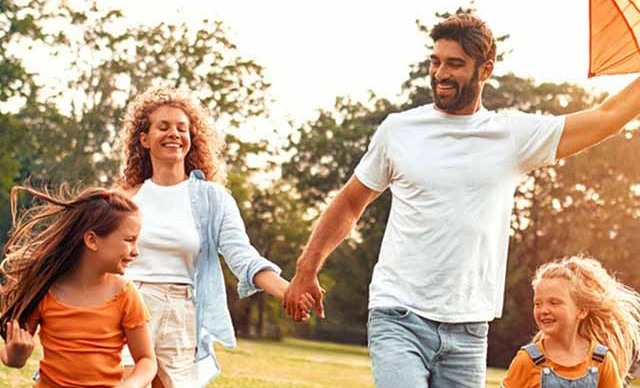 Mother and Father with two children flying a kite in a park