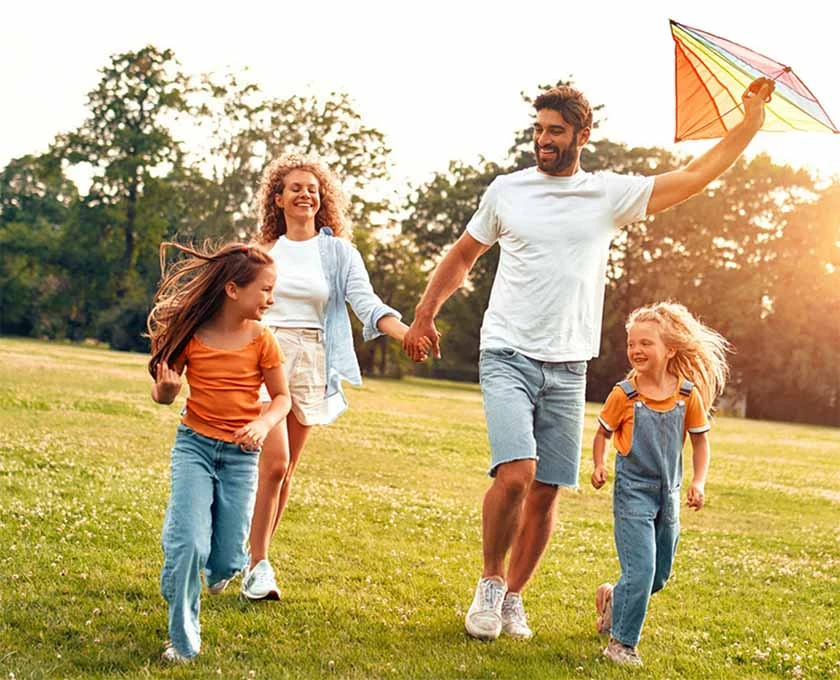 Mother and Father with two children flying a kite in a park