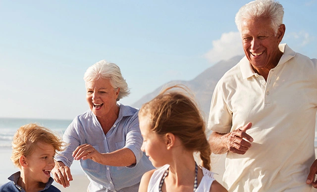An older couple with their grandchildren walking along a beach