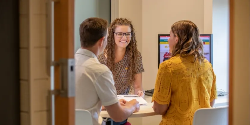 A staff member talking to two Members