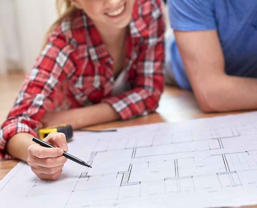 Close up on house plans with two people looking over them