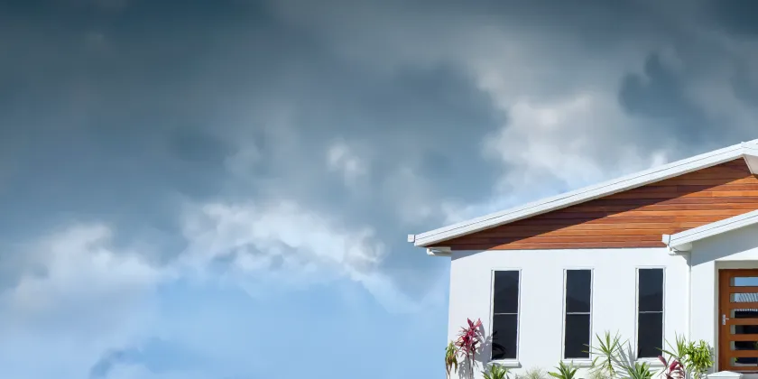 Modern house exterior beneath dark storm clouds, illustrating severe weather and storm season risks.