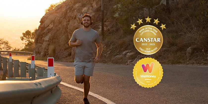 Person jogging along a curved mountain road at sunset, wearing headphones. A gold Canstar award badge and a WeMoney award badge are displayed on the right side of the image.