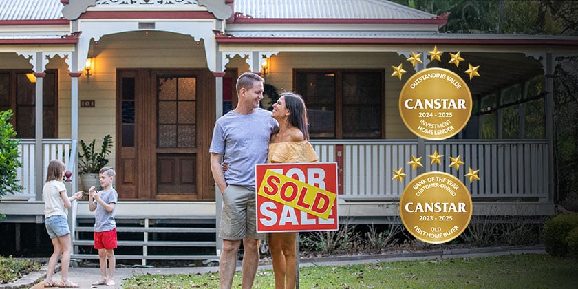 Couple standing in front of a traditional-style house holding a red and white "Sold" sign, with two children playing nearby on the lawn. Two gold Canstar award badges are displayed on the right side of the image.