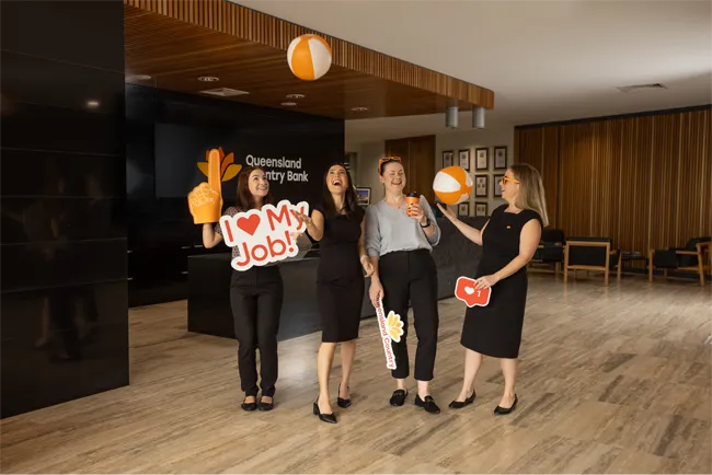 Group of four people celebrating at Queensland Country Bank Head Office