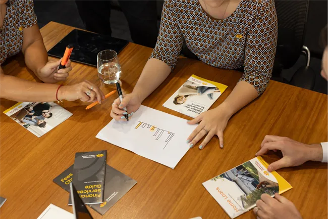 Overhead view of three people working on financial documents at a table