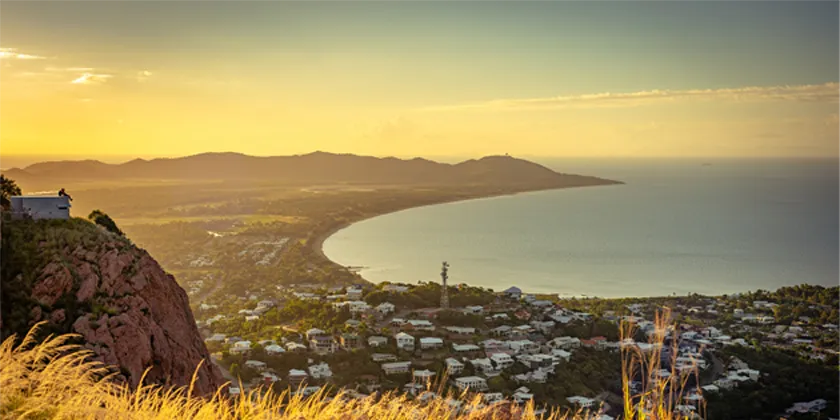 Panoramic view of Townsville coastline at sunset, with golden light over the landscape.