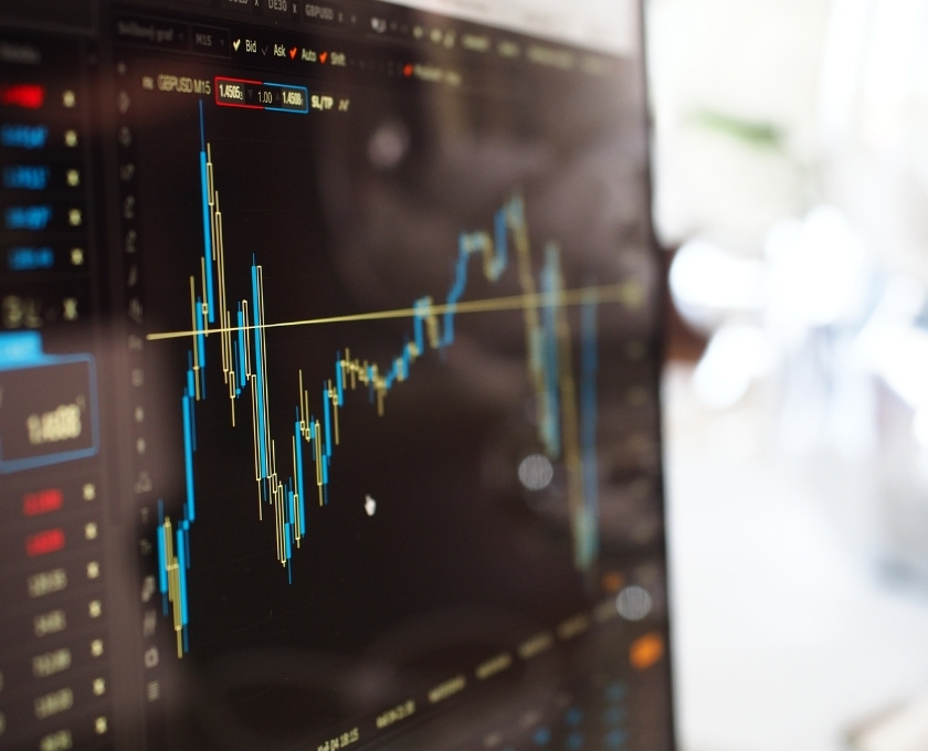 Close-up of a computer screen displaying a fluctuating financial chart with candlestick patterns, representing investment trends - used to illustrate the risks of investment scams.