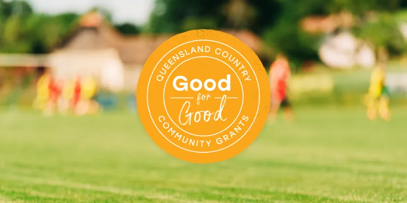 Queensland Country Bank Good for Good Community Grants logo displayed over a blurred outdoor sports field.