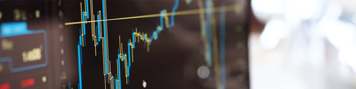 Close-up of a computer screen displaying a fluctuating financial chart with candlestick patterns, representing investment trends - used to illustrate the risks of investment scams.