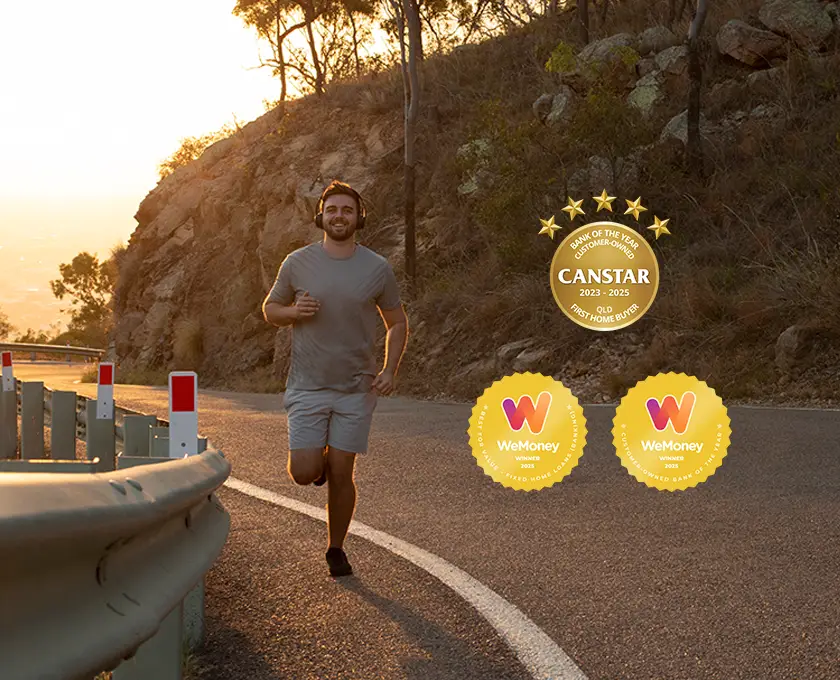 Person jogging along a winding road beside a rocky hillside at sunset, with safety barriers on the roadside and award badges displayed on the right.