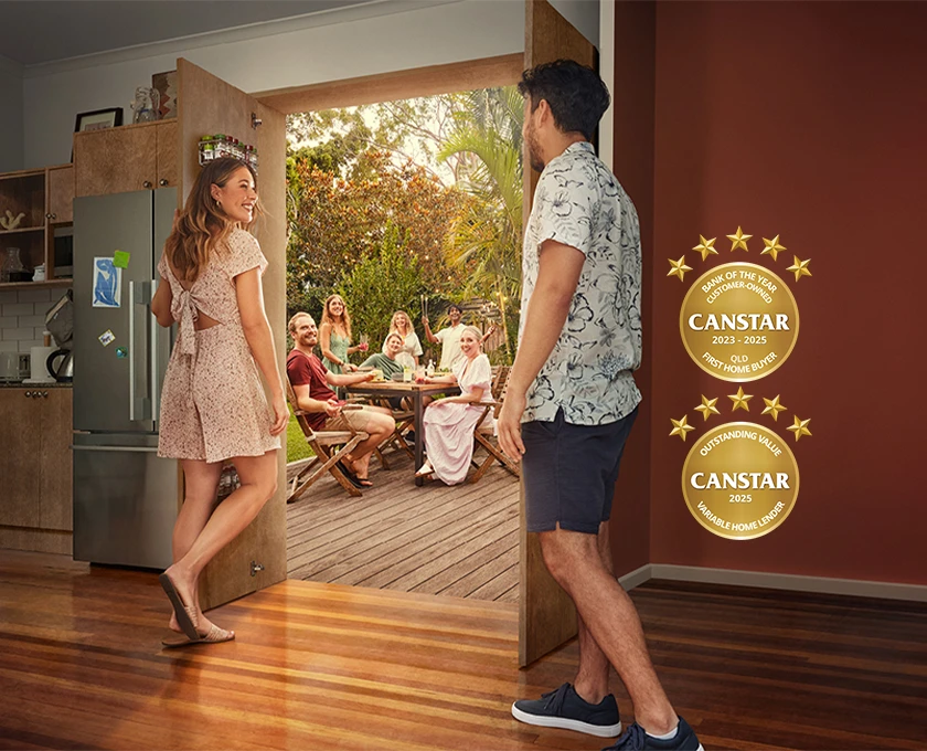 A couple in a modern kitchen walks toward an open door leading to a backyard gathering where friends are seated around an outdoor table, with two Canstar award badges displayed on the right side of the image.